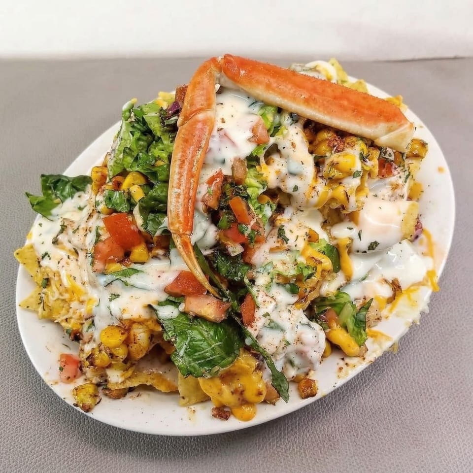 Flava Shack Seafood nachos with crab legs, corn, lettuce, tomatoes, and white sauce.
