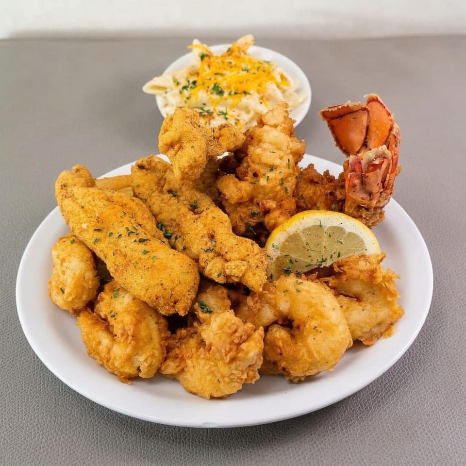 Flava Shack Seafood platter with fried fish, shrimp, lobster tail, lemon, and mac and cheese.
